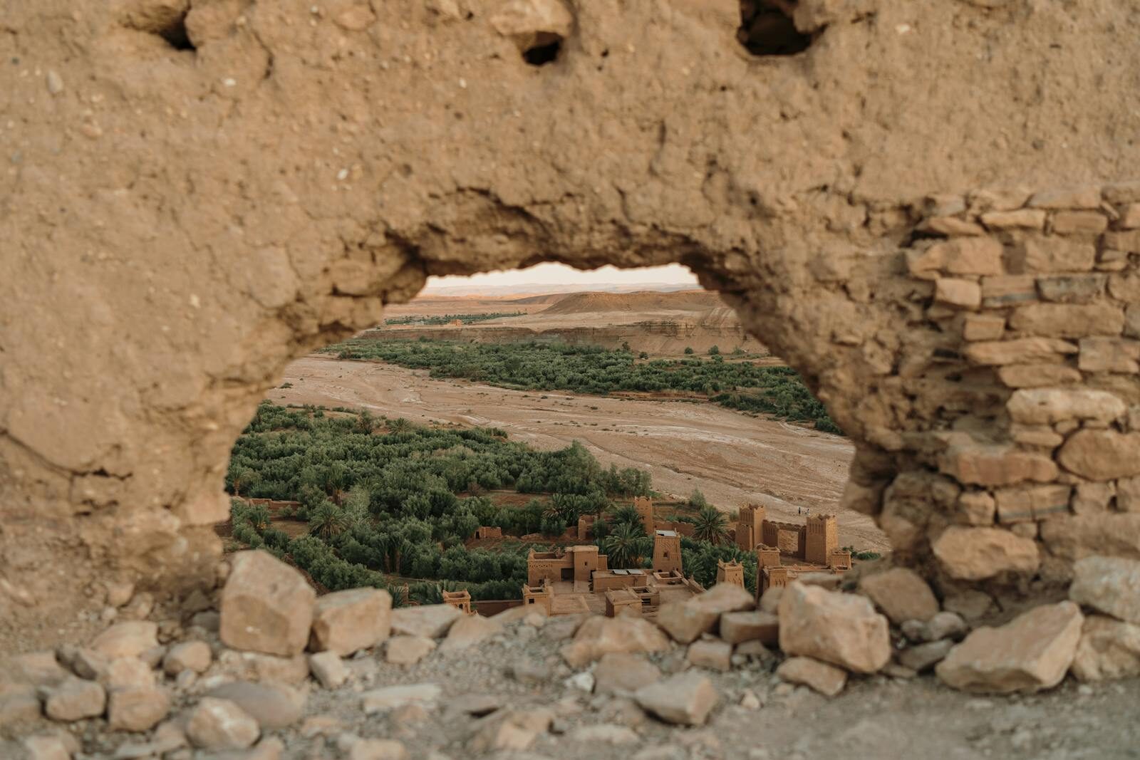 View of a historic village in Ouarzazate through ancient ruins in the desert landscape.