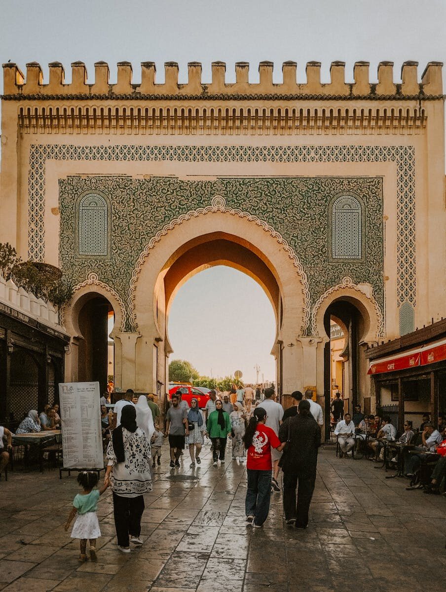 People walking through the historic Blue Gate in Fes Medina, Morocco, showcasing vibrant Moroccan architecture.