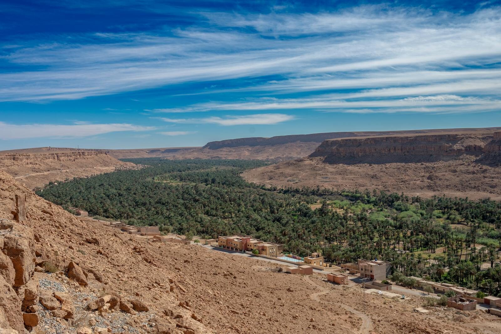 Scenic view of an oasis and desert landscape in Errachidia, Morocco, under a clear blue sky.