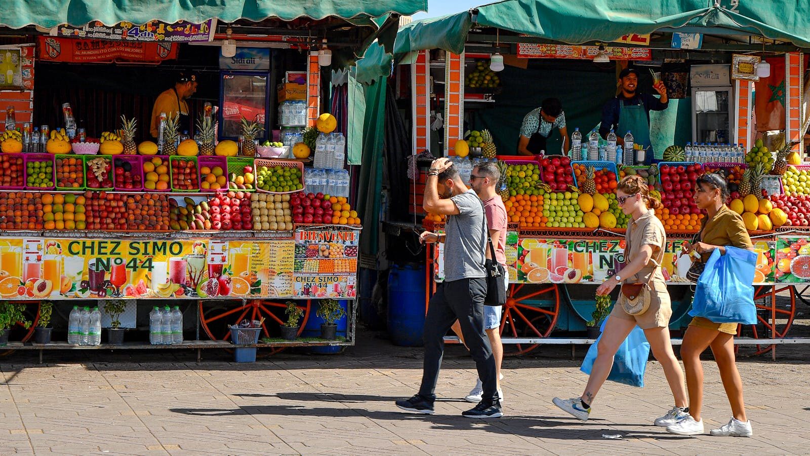 Colorful stalls of fresh produce at a bustling street market in Marrakesh, Morocco.