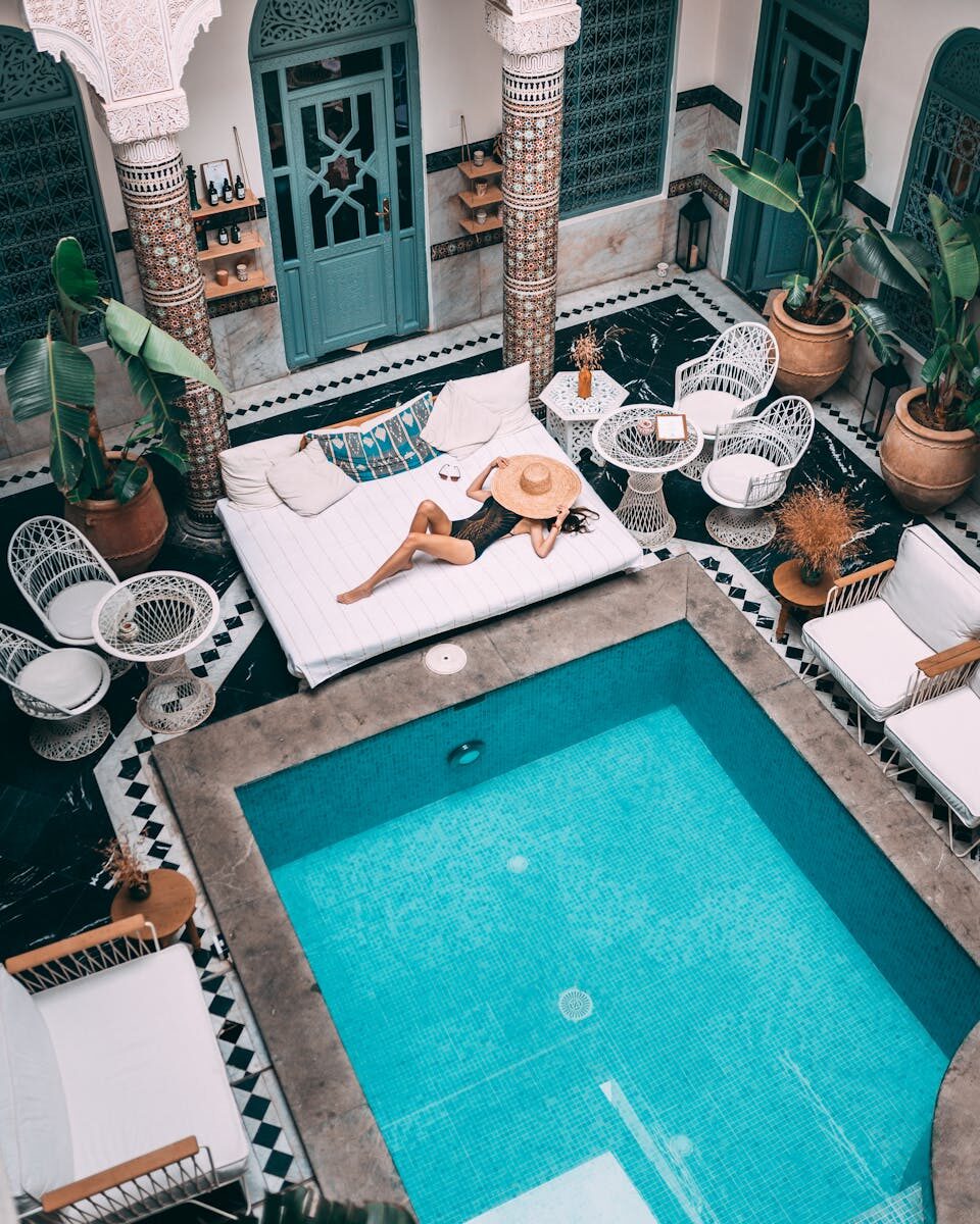 Elegant indoor pool with a woman lounging, set within a Moroccan riad in Marrakesh.