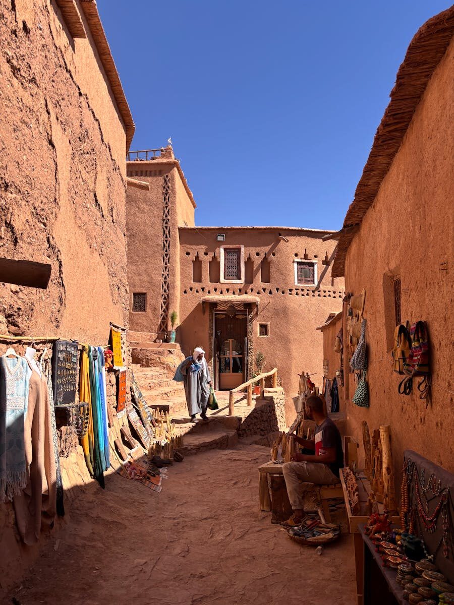 Colorful marketplace in Aït Benhaddou, Morocco, showcasing traditional Berber crafts under a clear blue sky.
